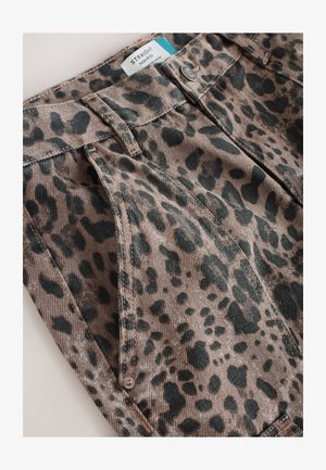 Wysokie spodnie o prostych nogawkach z nadrukiem w cętki w odcieniach brązu i czerni. Posiadają szlufki na pasek oraz zapięcie na guziki z przodu, wykonane z tekstury sztruksu.