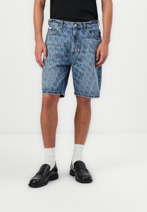 Denim shorts with a light blue, faded pattern and frayed hem. Worn with white socks and black loafers, against a plain white background.