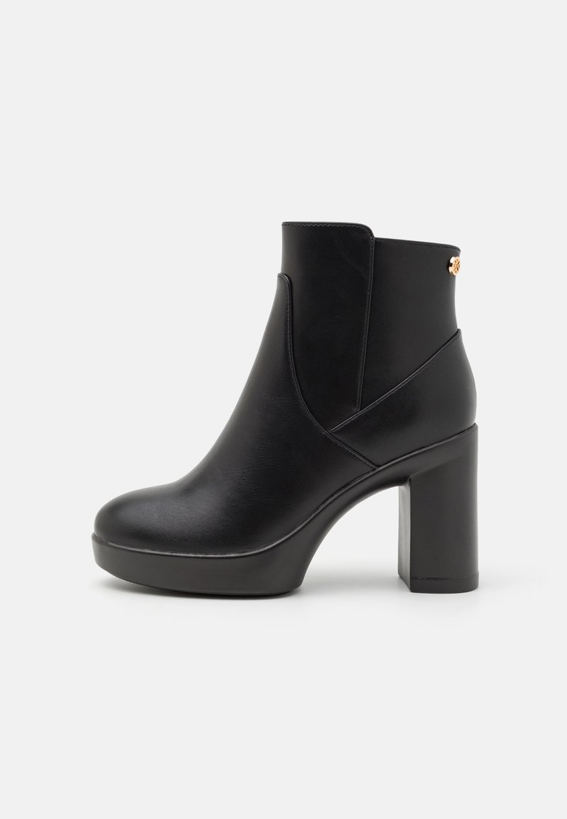 Bottine en cuir noir avec un bout arrondi, un talon bloc haut et un accent en métal doré à l'arrière. Texture lisse avec des coutures minimales.