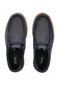 Navy blue suede and textured fabric slip-on shoes with brown rubber soles, featuring round laces and a patterned design on the upper.