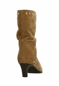 Bruine suède mid-calf laars met kleine gouden studs langs de bovenkant en zijkant, voorzien van een lage gebogen houten hak.