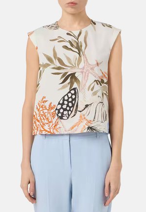 Blusa bianca senza maniche con motivi multicolore di vita marina e coralli, abbinata a pantaloni azzurri a vita alta.