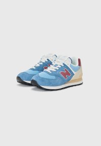 Light blue suede sneakers with mesh accents and dark blue sole. Features a red "N" logo and cream-colored heel cap. Lace-up design.