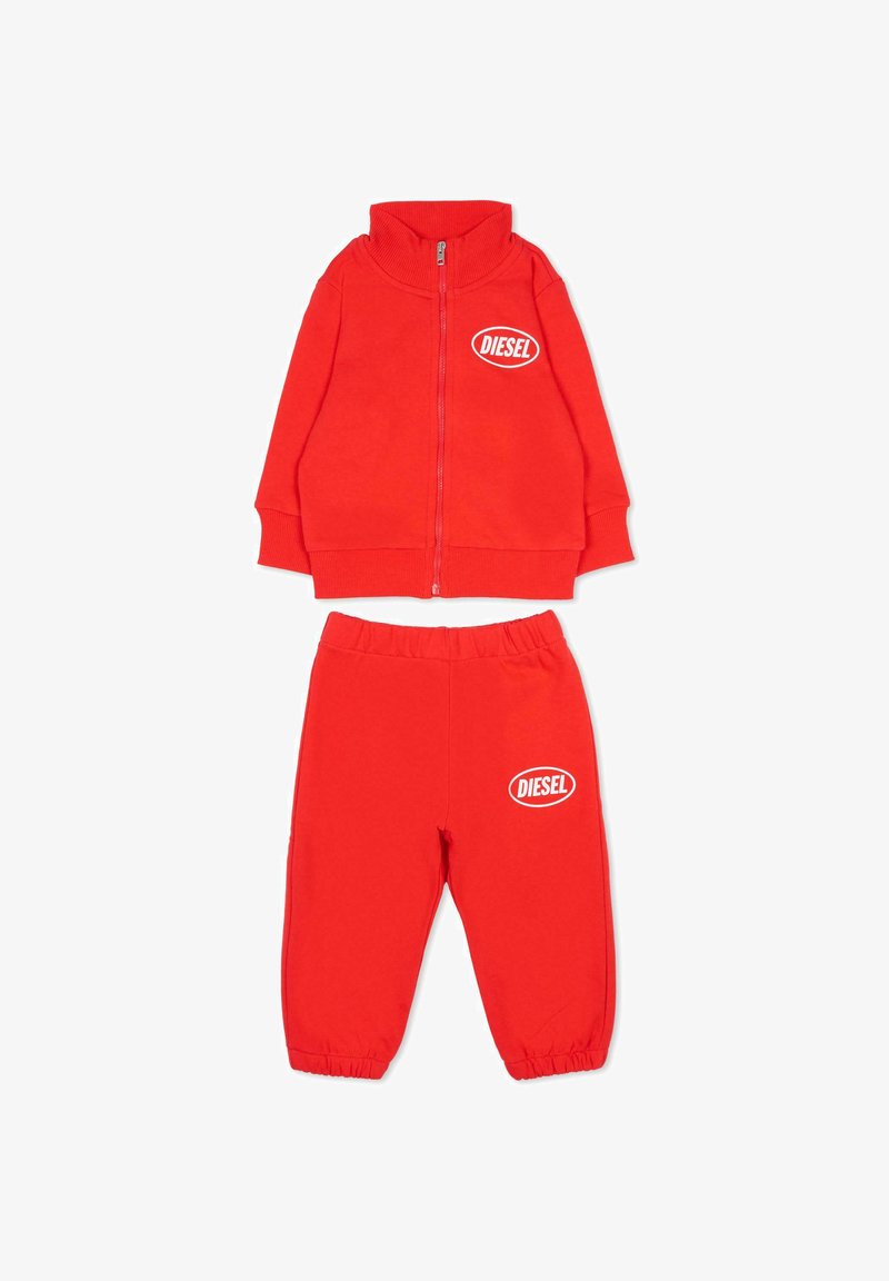 Rode trainingspakset met een jas met rits en hoge kraag en bijpassende broek met elastische taille, beide versierd met een wit Diesel-logo.