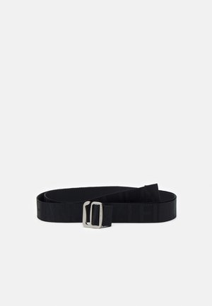 Ceinture en tissu noir avec boucle rectangulaire argentée, présentée enroulée sur fond blanc.