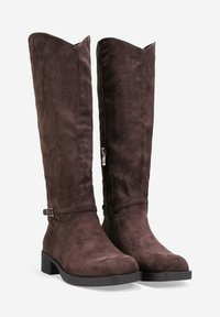 Botas altas de ante marrón con una textura suave, punta cuadrada y tacón bajo. Presenta una correa decorativa y cremallera lateral.