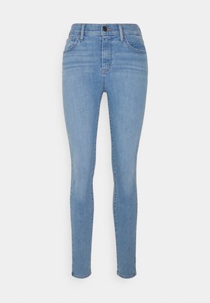 Jeans de mezclilla ligeros de corte slim fit en azul claro, con una cintura alta, que cuentan con cierre frontal de botón y diseño clásico de cinco bolsillos. Textura suave.