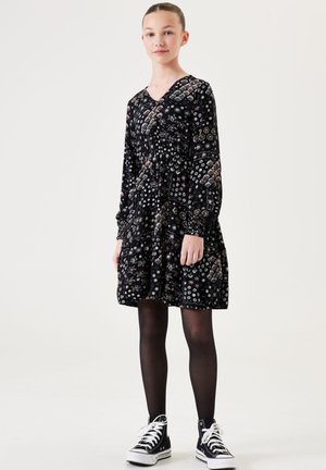 Schwarzes Blumenkleid mit langen Ärmeln, V-Ausschnitt, geraffter Taille und einem gestuften Rock, der verschiedene farbenfrohe Muster und Texturen aufweist.
