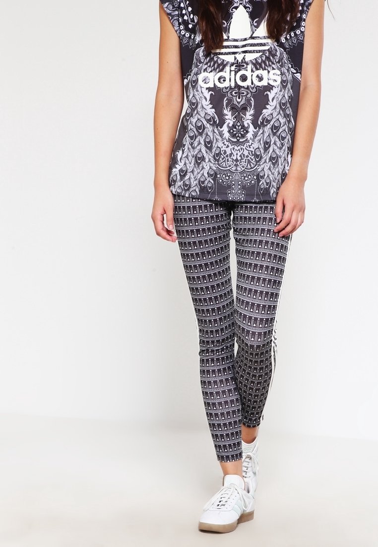 Svartvita mönstrade leggings och en matchande kortärmad t-shirt med grafisk design, där Adidas-logotypen är framträdande.