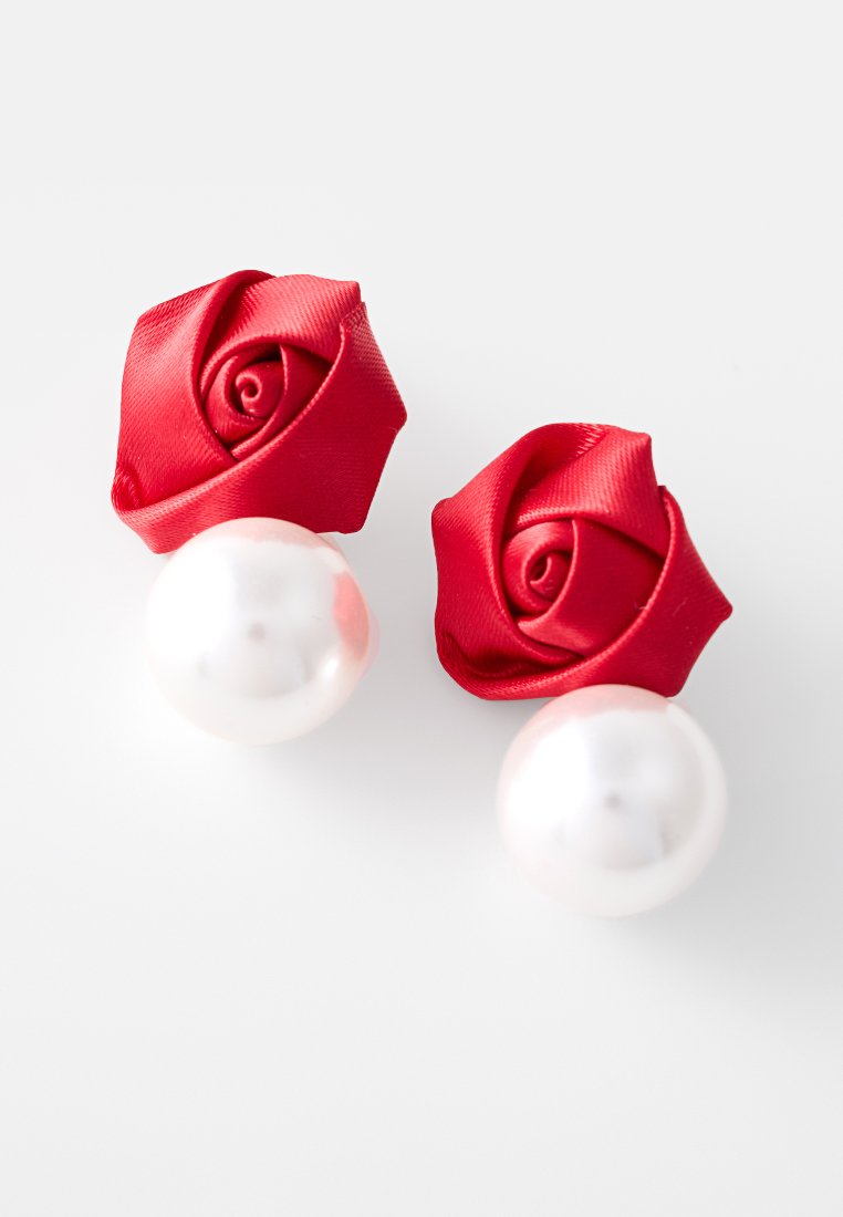 Orecchini a forma di rosa in raso rosso con una perla bianca liscia che pende al di sotto. Design compatto con un elegante contrasto di materiali.