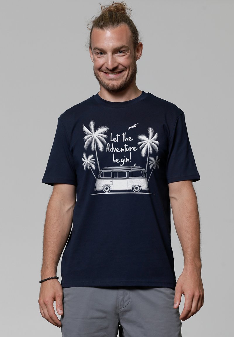 Navyblauwe katoenen t-shirt met een afbeelding van een vintage busje en palmbomen met de tekst "Laat het avontuur beginnen!" in het wit.