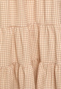 Tecido em padrão xadrez pêssego e bege com um design em camadas e pregueado. Apresenta um padrão de pequenas check com uma textura suave e leve.