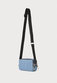 Modrá tkaninová crossbody taška s obdĺžnikovým tvarom, čierny nastaviteľný popruh s logom, strieborný zips a textúrovaný povrch.