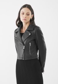 Zwarte leren cropped motorjack met zilveren ritsen, drukknopen kraag en aansluitende mouwen. Textuurstof voegt structuur toe.