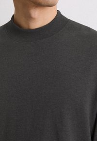 Ciemnoszara bluza z okrągłym dekoltem, wykonana z miękkiej, teksturowanej tkaniny. Posiada prążkowany dekolt oraz bezszwowy design dla czystego wyglądu.