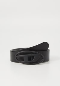 Cinturón de cuero negro con una hebilla ancha en forma ovalada que presenta un diseño recortado. Textura suave y diseño minimalista. Longitud ajustable.