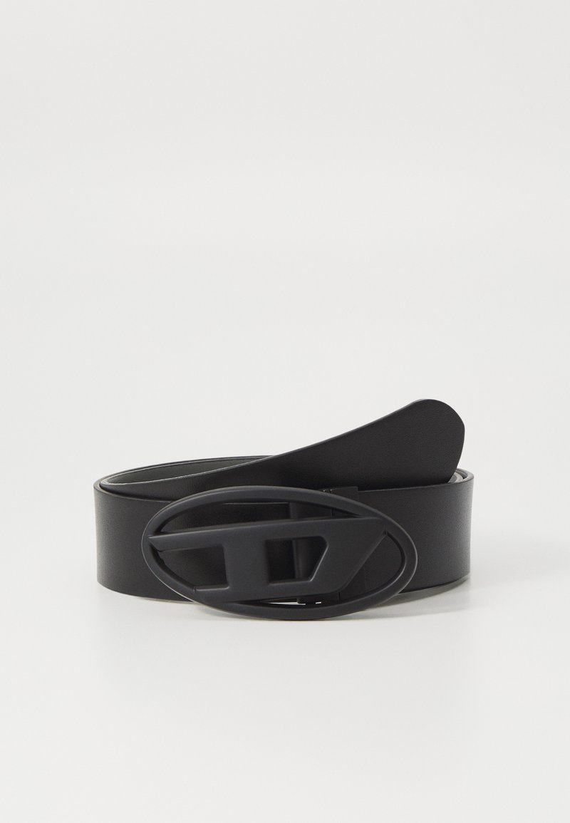 Cinturón de cuero negro con una hebilla ancha en forma ovalada que presenta un diseño recortado. Textura suave y diseño minimalista. Longitud ajustable.