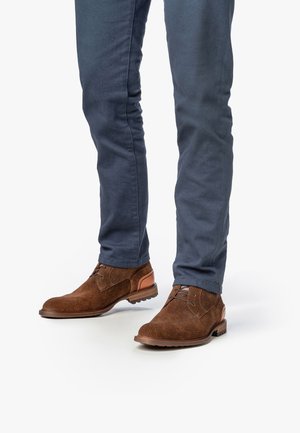 Braune Fischgrat-Leder Schuhe mit strukturiertem Obermaterial, runden Zehen und kontrastierenden hellbraunen Akzenten, kombiniert mit hellblauen Slim-Fit-Hosen.