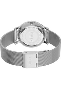 Hõbedane võrgu randmekaelakee ümaralt poleeritud korpusega. Valge dial on varustatud "TIMEX" logo ja tähistustega. Roostevabast terasest klamber tagab rihma kindluse.
