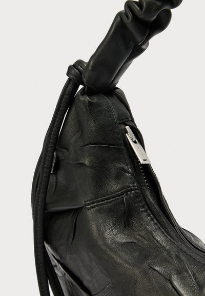Geantă de mână din piele neagră cu o suprafață texturată, având un mâner noduros și un fermoar argintiu pe o parte pentru închidere.