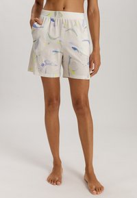Lichte, beige shorts met een aquarelpatroon in blauw en groen, voorzien van een elastische tailleband en zijzakken.