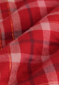 Červenobílá károvaná látka s měkkou texturou, charakteristická klasickým kostkovaným vzorem a jemnými oranžovými prošívacími akcenty.