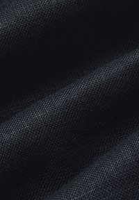 Czarna tkanina pleciona wykazuje teksturową powierzchnię z widocznymi włóknami. Materiał wydaje się trwały, o gładkim, ale lekko chropowatym wykończeniu.