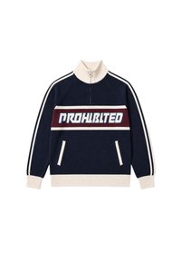 Pull en maille bleu marine et crème avec demi-fermeture éclair, manches rayées, deux poches avant et texte "PROHIBITED" sur une bande poitrine rouge et blanche.