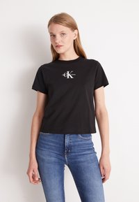 Zwarte katoen t-shirt met korte mouwen en een ronde halslijn, met in het midden een witte 'Calvin Klein Jeans' logo.