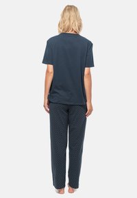 T-shirt en coton navy à manches courtes associé à un pantalon de pyjama navy à pois, le tout en tissu léger, texture douce et coupe décontractée.