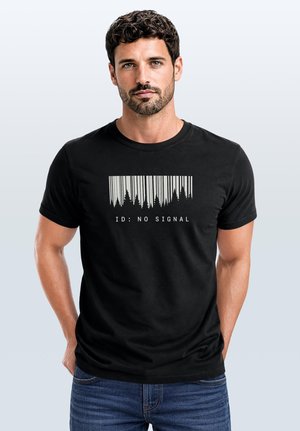 Man with short curly hair and beard wearing black t-shirt with barcode and tree silhouettes above text reading "ID: NO SIGNAL."