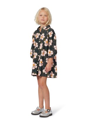 Een bloemenpatroon jurk in donkergroen met lichtroze bloemen, voorzien van een knopenfront, lange mouwen en een losse pasvorm. Zilveren schoenen met accenten.