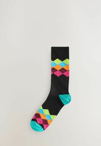 Sort sok med et farverigt argyle-mønster i pink, grøn, blå og orange diamanter. Tåen og hælen er turkise.