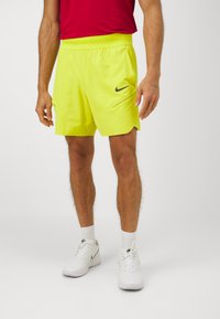 Svijetlo žute Nike šortse s elastičnom trakicom u struku, bočnim džepovima i crnim logotipom sprijeda. Glatko, lagano platno.