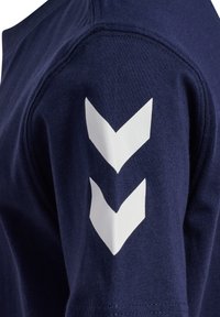 Marineblå t-shirt med blødt, tekstureret stof og hvide chevronmønstre på venstre ærme. Kortærmet med rund hals.