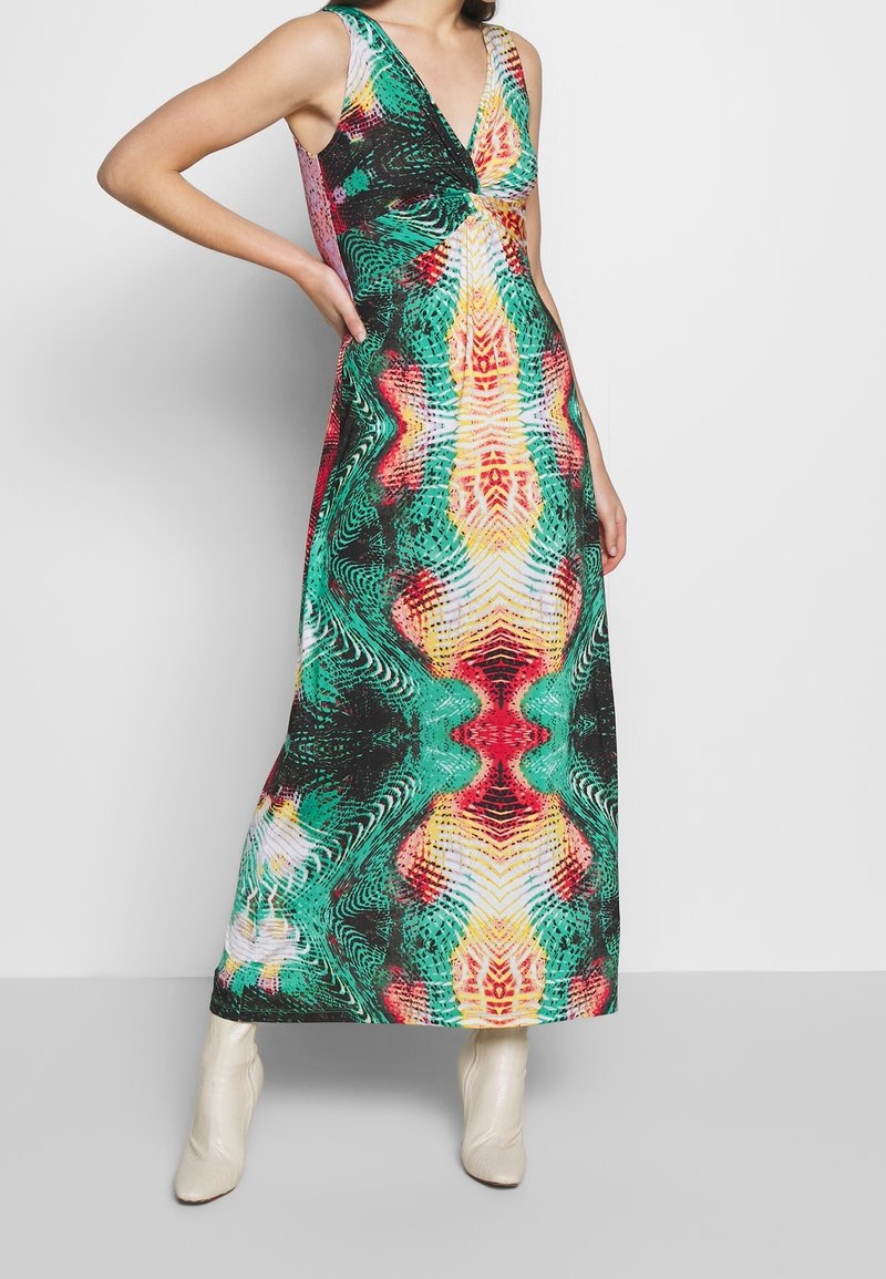 Robe maxi avec un décolleté en V profond, motif abstrait coloré en vert, rouge et jaune, et une silhouette près du corps.