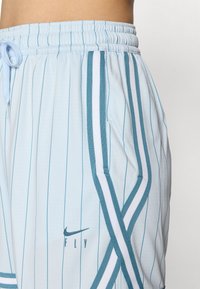 Ljusblåa träningsshorts med vita vertikala ränder, elastisk midja, justerbar dragsko och sidofickor. Nike-logga på framsidan.