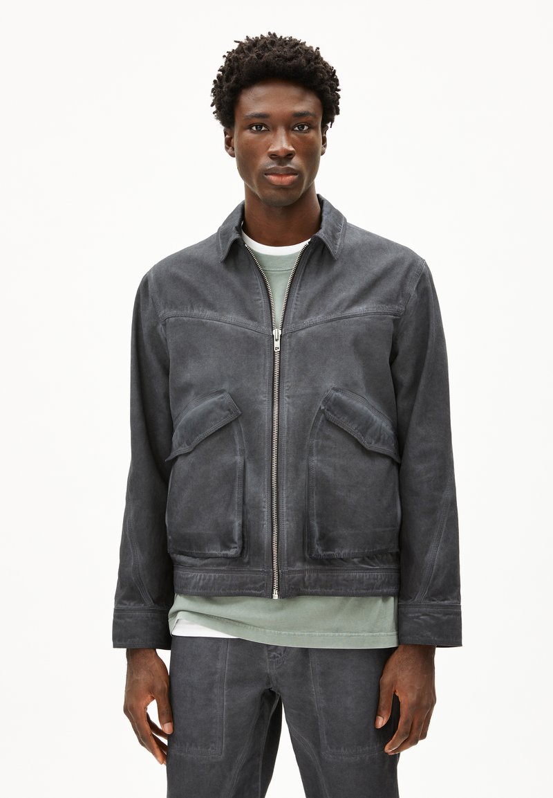 Dunkelgraue Jacke aus weichem Stoff, mit einem Reißverschluss vorne, zwei frontalen Taschen und einem lässigen Design mit Kragen.