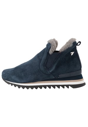 Zapatos de ante azul marino tipo slip-on con cuello de piel sintética gris, suela texturizada y rayas en blanco y beige contrastantes en la suela.