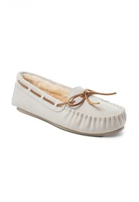 Zapatilla de ante beige claro con un interior suave, un delicado lazo decorativo y costuras decorativas a lo largo de los bordes, que cuenta con una suela de goma flexible.