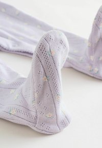 Lila strumpbyxor med blommönster och texturerade detaljer. Tyget är stickat med en intrikat design vid anklar och tår.