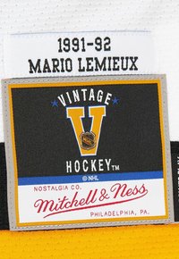 Patch von 1991-92 mit Mario Lemieux, versehen mit dem Vintage Hockey-Logo und dem Etikett der Marke Mitchell & Ness auf einem gelb-weißen Stoffhintergrund.