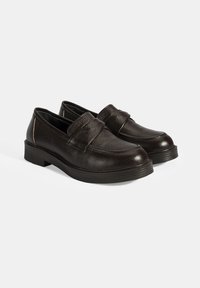 Zwarte leren loafers met een gestructureerde afwerking, voorzien van een gestikte band over de voorkant, een lage blokhak en een rubberen zool.