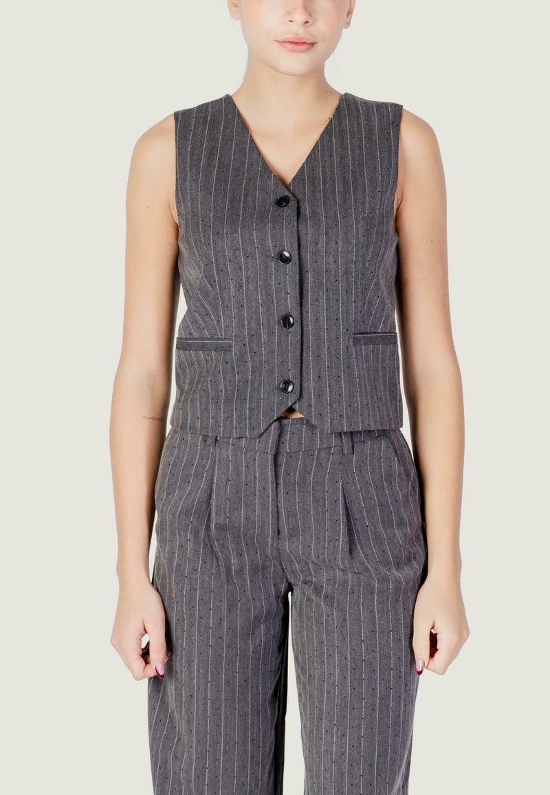 Gilet smanicato grigio a righe con scollo a V, bottoni frontali e tasche laterali, abbinato a pantaloni coordinati con righe verticali.
