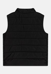 Chaleco acolchado negro con cuello alto, costuras horizontales y una textura suave. Sin mangas, diseñado para superponerse y para proporcionar calor.