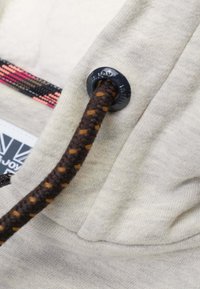 Lichtgrijze hoodie stof met een geweven, donkerbruine trekkoord met oranje stippen en een metalen oogje detail.