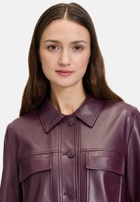 Fioletowa skórzana kurtka z wyrazistym kołnierzem, zapięciem na guziki oraz dwiema przednimi kieszeniami. Gładka tekstura z dopasowanym krojem.
