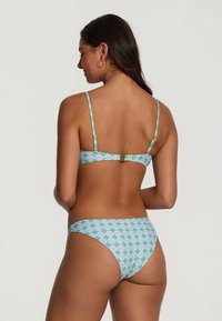 Bikini komplektas su žaliais, violetiniais ir baltais gėlių raštais. Ploni diržai, sagtis nugaroje ir vidutinė aprėptis apatinėse dalyse.