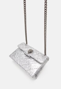 Stříbrný glitrový psaníčko s řetízkem, prošívanou texturou, uzávěrem na cvak a dekorativním kováním na přední straně.