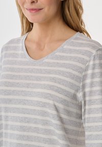 Camiseta de cuello en V a rayas gris claro, con una textura suave y lisa, que presenta rayas alternando entre oscuro y claro en un diseño casual.